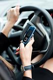 Close-up of a businesswoman sending a text while driving