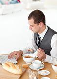Young businessman using a laptop while having breakfast 