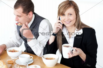 Smiling businesswoman talking on phone while having breakfast wi