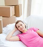 Pensive woman relaxing on a sofa with boxes