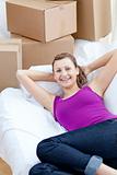 Portrait of a cute woman relaxing on a sofa with boxes 