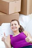 Portrait of a radiant woman relaxing on a sofa with boxes 