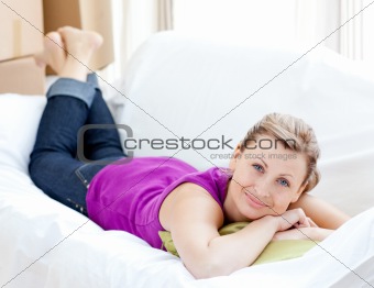 Portrait of a joyful woman relaxing on a sofa with boxes 