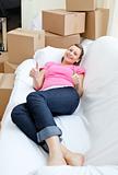 Bright woman relaxing on a sofa with boxes