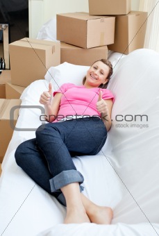 Bright woman relaxing on a sofa with boxes