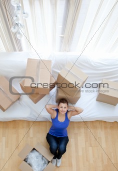 Exhausted woman sitting between boxes at home