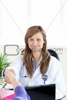 Attractive female doctor shaking a hand 