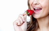 Close-up of a young woman eating a strawberry 