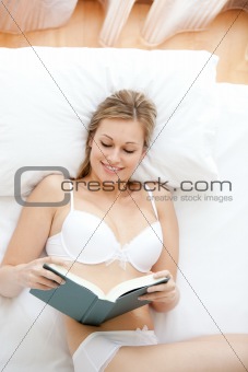 Smiling woman in underwear reading a book 