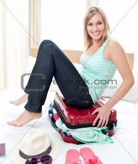 Attractive woman trying to close her suitcase