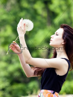Girl is blowing on dandelion.