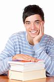 Young happy smiling male student sitting on desk with books