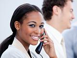 Positive Afro-American businesswoman talking on phone in the office
