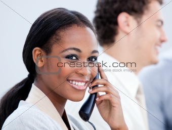 Positive Afro-American businesswoman talking on phone in the office