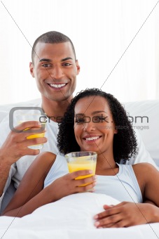 Enamored couple drinking lying on their bed