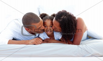 Cheerful parents kissing their daughter