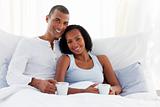 Afro-american couple drinking a coffee on their bed