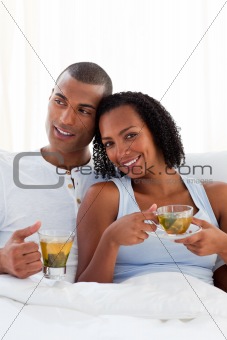 Intimate couple drinking a cup of tea on their bed
