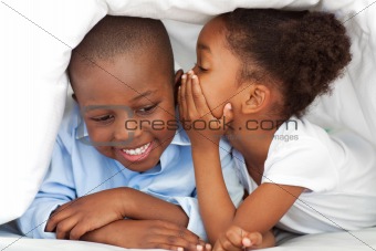 Ethnic little girl whispering something to her brother
