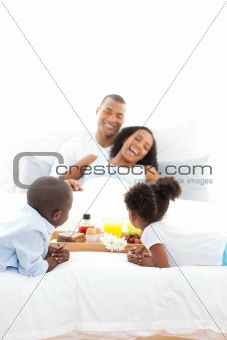 Cheerful family having breakfast in the bedroom