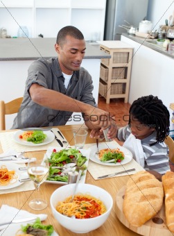 Caring father helping his son cut vegetables in the kitchen
