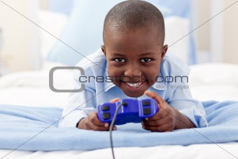 Little boy playing video games and lying on bed