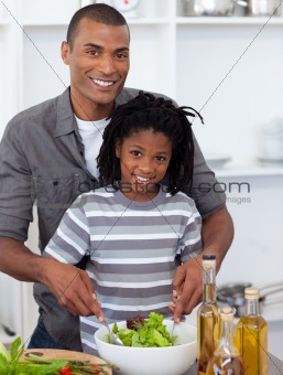 Smiling little boy preparing salad with his father