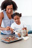 Afro-american little girl preparing biscuits with her mother 