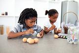 Concentrated Afro-american siblings painting eggs 