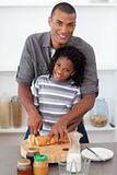 Smiling father and his son cutting bread 