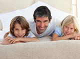 Caring father and his children lying on a bed