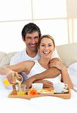 Romantic couple having breakfast lying in the bed