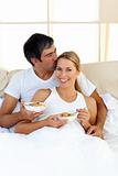 Affectionate couple eating cereals lying in the bed