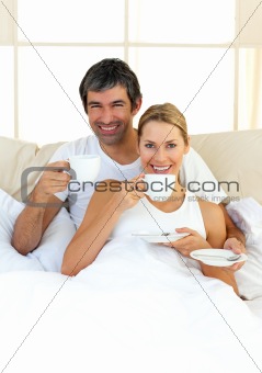 Enthusiastic lovers drinking coffee lying in the bed