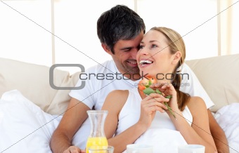 Beautiful couple having breakfast lying in the bed