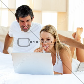 Cheerful couple relaxing on their bed at home