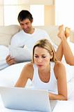 Charismatic woman using a laptop lying on bed