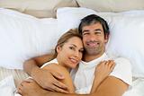 Smiling couple embracing lying in bed