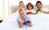 Cute blond child playing video game with her family