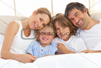 Happy family reading a book on bed