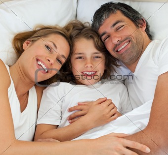 Happy family lying together on bed