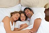 Cute child and his parents sleeping together