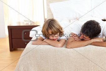 Earing father talking with his son lying on bed