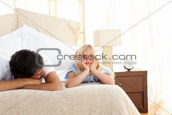 Sad little girl lying on bed with her father