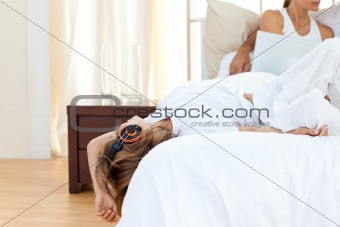 Cute boy listening music lying on bed