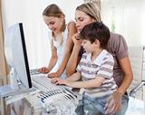 Attractive mother teaching her children how to use a computer 