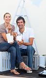 Smiling couple eating while decorating a room
