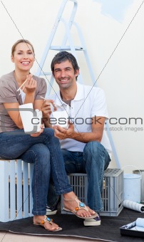 Smiling couple eating while decorating a room