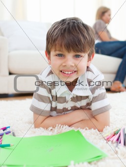Portrait of little boy drawing lying on the floor