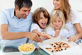 Excited children eating a pizza with their parents